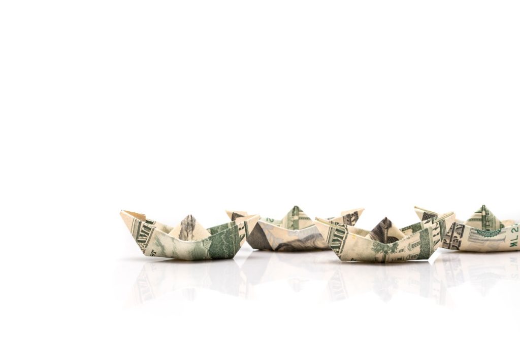 Can the creator economy stay afloat in a flood of AI slop? row of paper ships from dollar banknotes